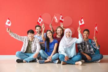 Group of students with Canadian flags sitting near color wall�