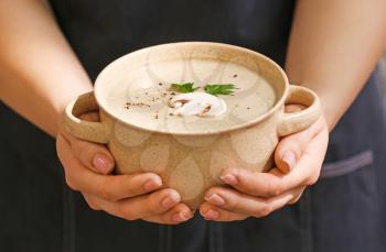 Woman holding pot of tasty mushroom cream soup, closeup�