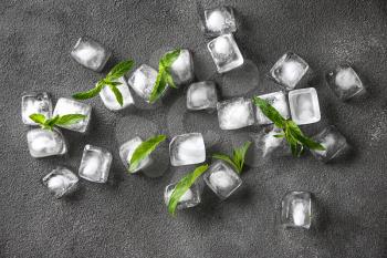 Ice cubes with green mint leaves on grunge background�