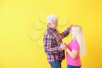 Portrait of happy dancing mature couple on color background�