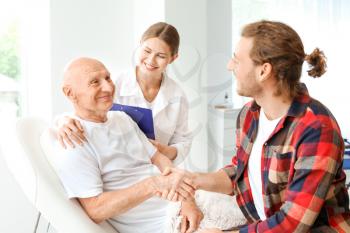 Young man visiting his elderly father in modern clinic 