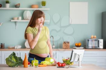 Beautiful pregnant woman with healthy vegetables in kitchen�
