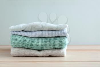 Stack of warm clothes on table against light background�