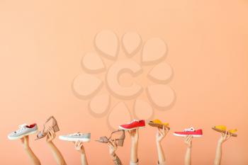 Female hands with different stylish shoes on color background�