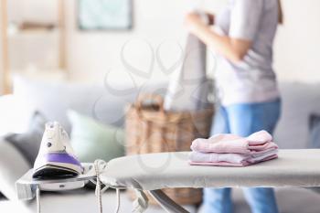 Stack of clean clothes on ironing board at home�