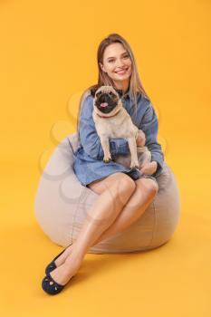 Beautiful young woman with cute pug dog on color background�