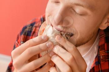 Man eating tasty taco on color background, closeup�
