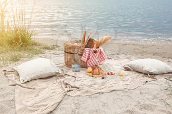 Wicker basket with tasty food and drink for romantic picnic near river�