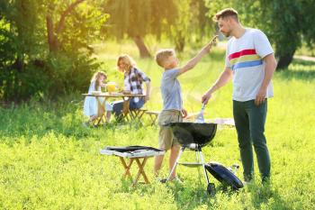 Father with son cooking tasty food on grill outdoors�