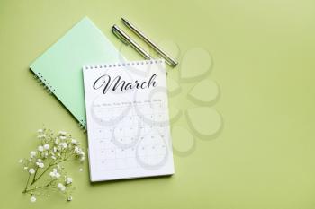 Flip paper calendar, notebook and flowers on color background�