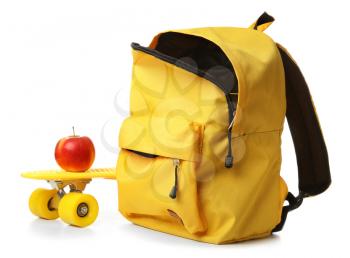 School backpack, skateboard and apple on white background�