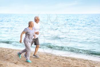 Sporty mature couple running on sea beach�