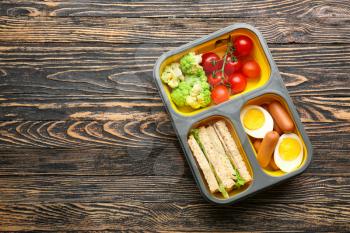Lunch box with tasty food on wooden background�