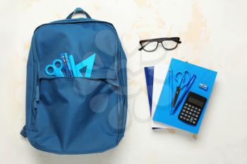 School backpack and stationery on light background�