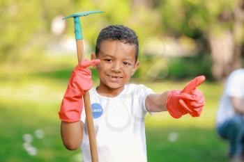 Little African-American volunteer with gardening rake in park�