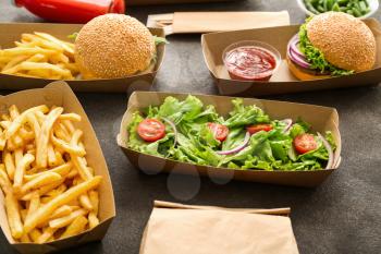 Containers with delicious food on grey background�