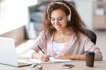 Young African-American student listening to music while preparing for exam�
