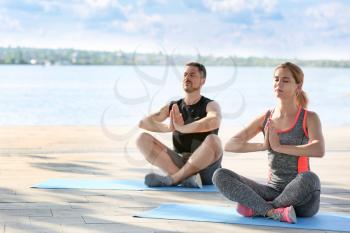 Sporty couple in love meditating outdoors�