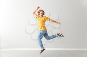 Handsome young man dancing against white wall�