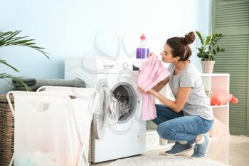 Beautiful young woman doing laundry at home�