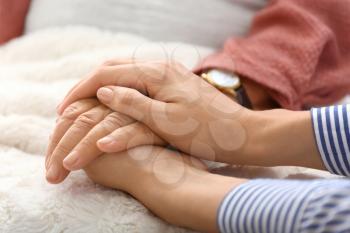 Young daughter supporting elderly mother at home, closeup�