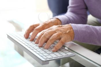 Elderly woman using modern computer keyboard at table, closeup�