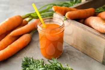 Jar of tasty carrot juice on grey table�