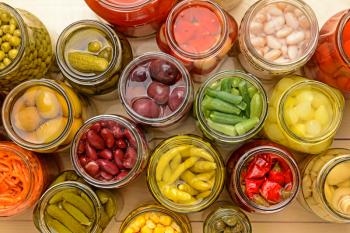 Jars with different canned vegetables on wooden background�