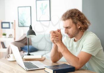 Religious young man praying at home�