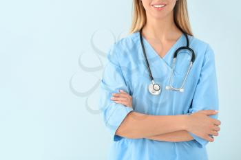 Female nurse with stethoscope on color background�