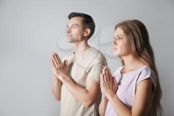 Religious couple praying to God on grey background�