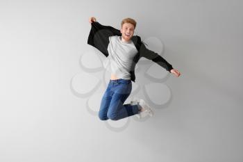 Handsome jumping young man against light background�