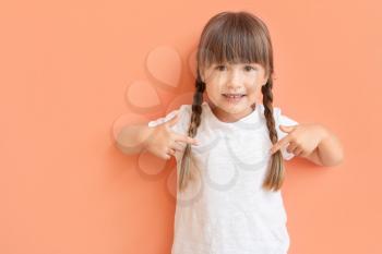 Little girl pointing at her t-shirt on color background�