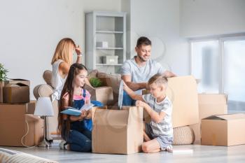 Happy family unpacking belongings in their new house�
