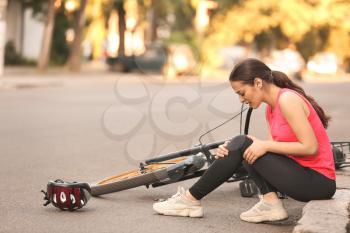 Sporty young woman fallen off her bicycle outdoors�
