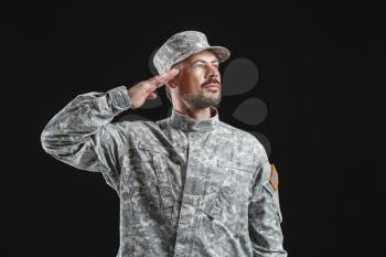 Saluting soldier on dark background�