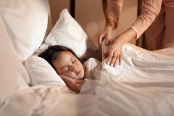 Woman putting her little daughter to bed�