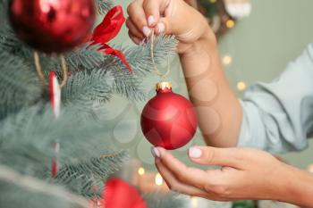 Woman decorating beautiful Christmas tree at home, closeup�