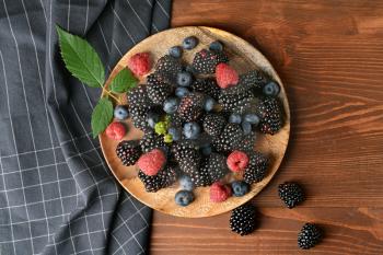 Plate with tasty berries on wooden table�