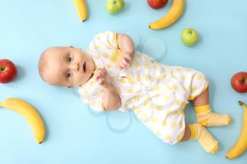 Adorable little baby with fruits on color background�