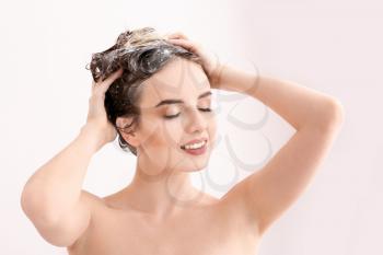 Beautiful young woman washing hair in shower�