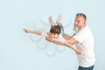 Cute little boy playing with grandfather on light background�