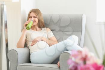 Beautiful pregnant woman drinking smoothie at home�