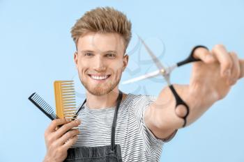 Young male hairdresser on color background�