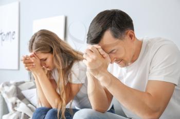 Religious couple praying to God at home�