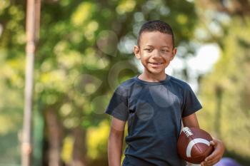 Cute little African-American boy with rugby ball in park�