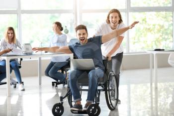 Handicapped young man with colleague having fun in office�