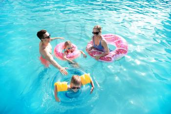 Happy family swimming in pool on summer day�
