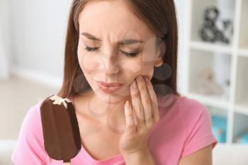 Young woman with sensitive teeth and cold ice-cream at home�