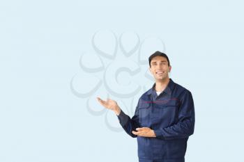 Male car mechanic showing something on color background�